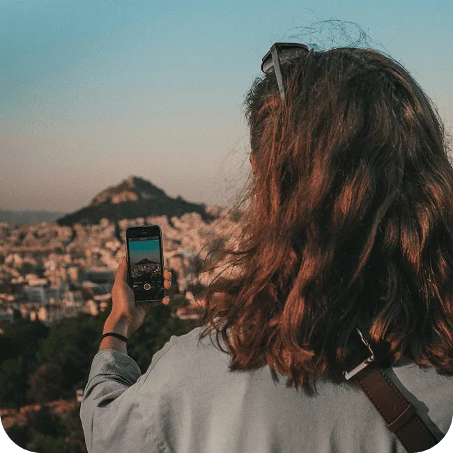 Frau fotografiert mit dem Smartphone den Blick über eine Stadt